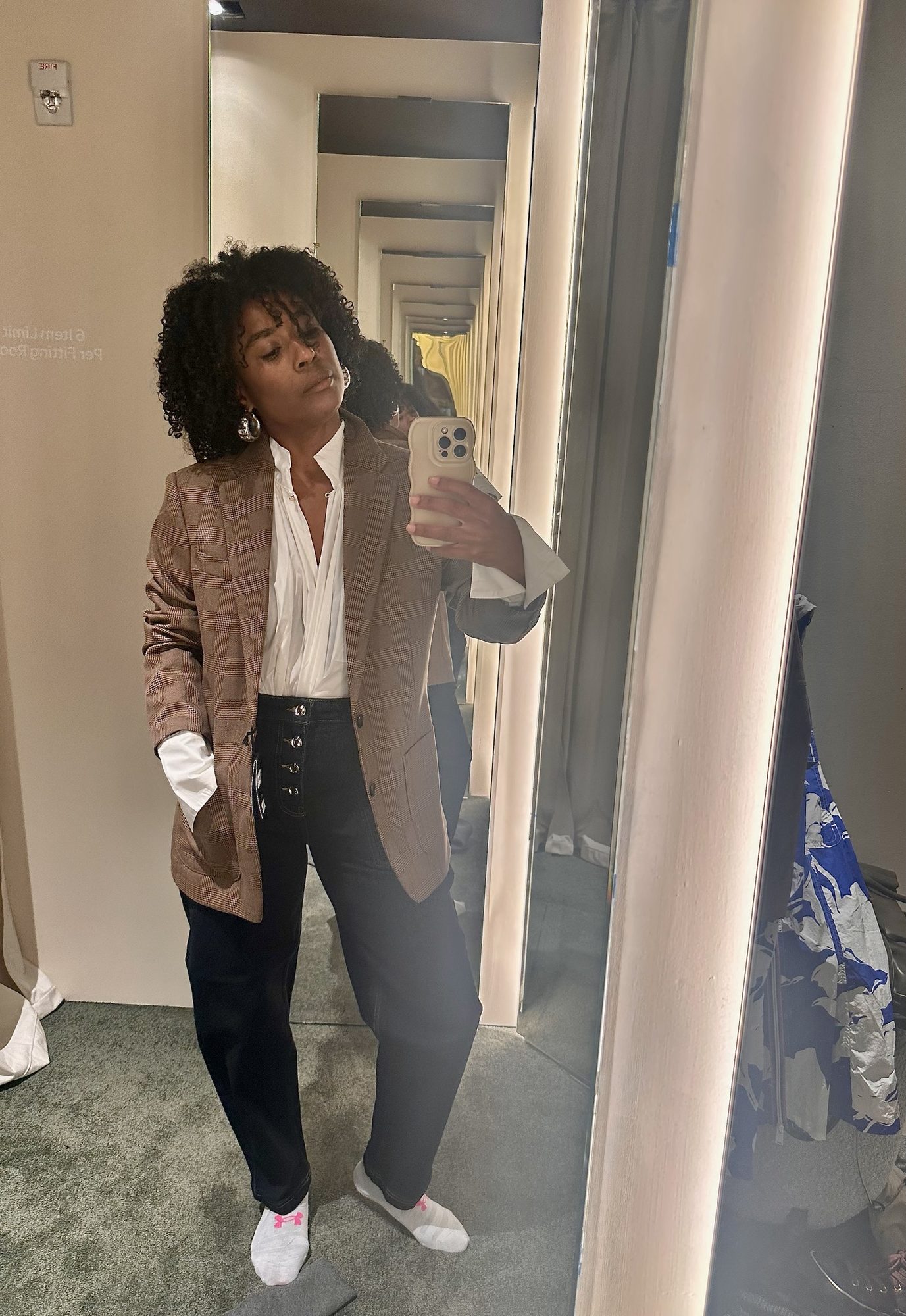 Abbie in the fitting room wearing the menswear blazer, white blouse and dark denim.